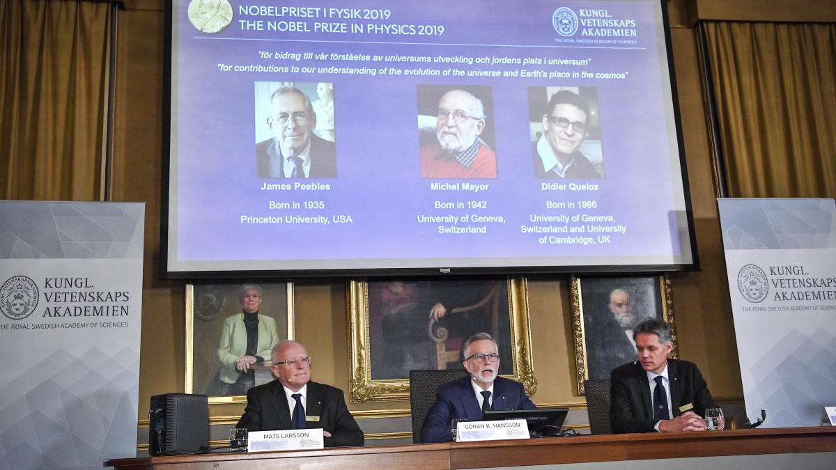 Goran K. Hansson, a Svéd Királyi Tudományos Akadémia titkára (k) az akadémia stockholmi sajtótájékoztatóján 2019. október 8-án bejelenti, hogy csillagászati kutatásokért James Peebles kanadai-amerikai kozmológus, Michel Mayor svájci asztrofizikus és a szintén svájci Didier Queloz csillagász (kivetítőn, b-j) kapja az idei fizikai Nobel-díjat.