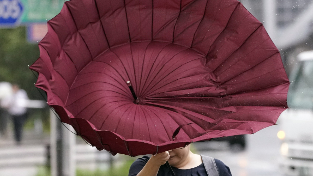 Kifordult az esernyője az erős szélben egy gyalogosnak az óránkénti 200 kilométeres sebességet is meghaladó széllökésekkel pusztító Faxaj tájfun elvonulása után Tokióban 2019. szeptember 9-én.