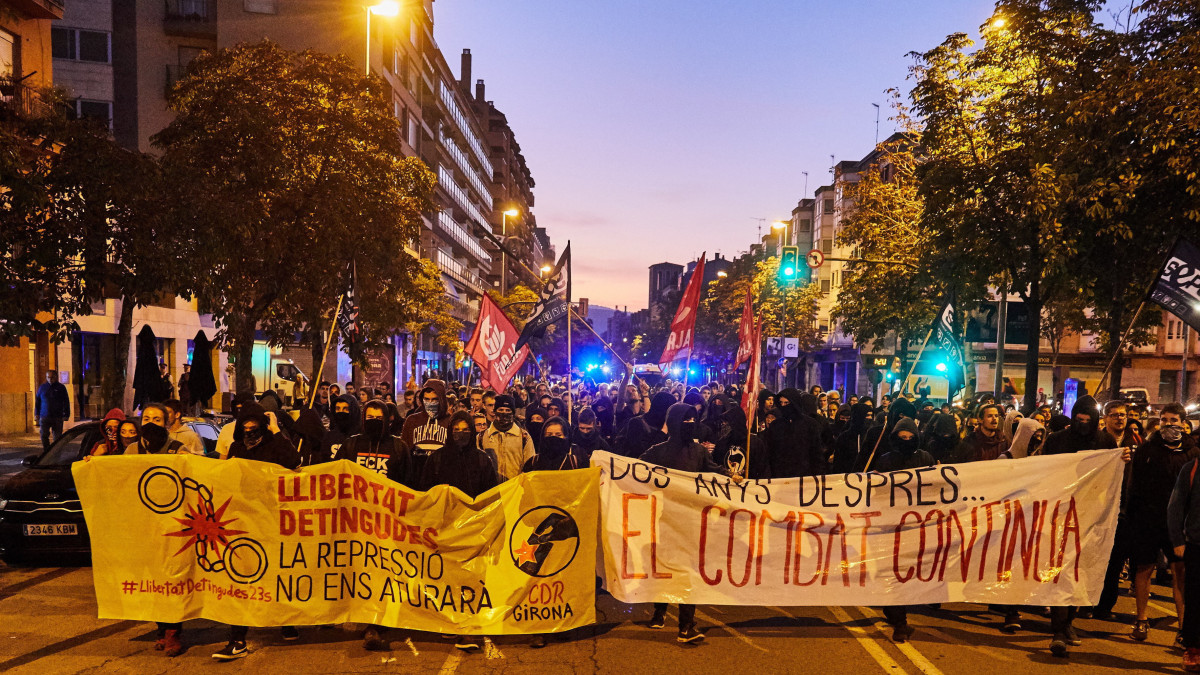 Szabadságot a foglyoknak  Az elnyomás nem állít meg minket (b) és Két évvel későbba harc folytatódik jelentésű transzparenssel vonulnak katalán függetlenségpárti tüntetők az alkotmányellenesnek nyilvánított katalán függetlenségi népszavazás második évfordulója alkalmából tartott megemlékezésen Gironában 2019. október 1-jén. Az autonóm régióban 2017. október 1-jén rendeztek népszavazást a függetlenedésről Spanyolországtól.