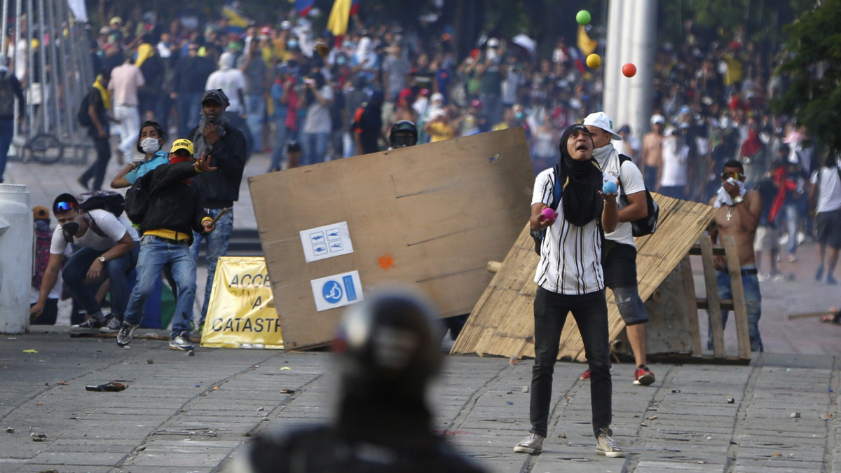 Tüntető zsonglőrködik a tiltakozók és rendőrök összecsapása közben a kolumbiai Caliban 2019. november 21-én. Az Ivan Duque államfő szociális és gazdaságpolitikája miatt erősödő erőszakhullám miatt kijárási tilalmat vezettek be a városban.