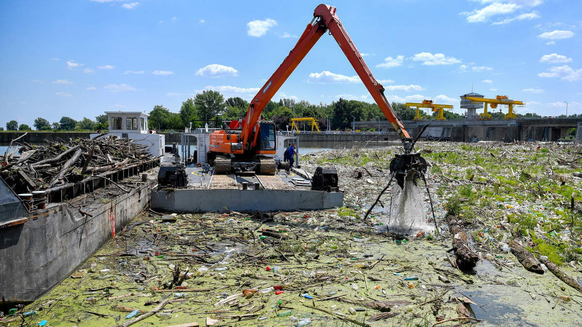 Uszályra rakodja a tavaszi árhullámokat követően összetorlódott mintegy nyolcezer tonna kommunális és növényi eredetű hulladékot egy munkagép a kiskörei vízlépcsőnél 2019. július 16-án. Vízügyi, civil és vállalati együttműködés segíti a Tisza hulladékmentesítését, az idén rekordméretű szennyezés felszámolása legalább négy hónapot vesz majd igénybe.