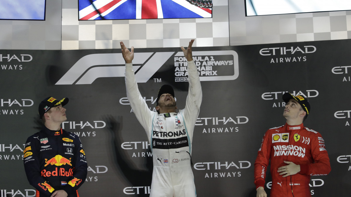 Lewis Hamilton, a Mercedes brit versenyzője (k) ünnepel a trófeával a győzelmi emelvényen, miután megnyerte a Forma-1-es autós gyorsasági világbajnokság abu-dzabi futamát a Yas Marina versenypályán 2019. december 1-jén. Balról a második helyezett Max Verstappen, a Red Bull holland, jobbról a harmadik helyen végzett Charles Leclerc, a Ferrari monacói versenyzője.