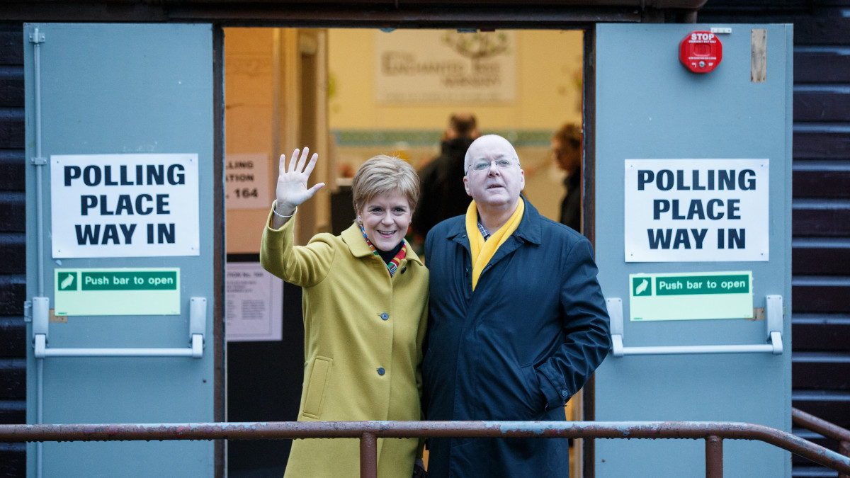 Nicola Sturgeon skót miniszterelnök, a függetlenségre törekvő Skót Nemzeti Párt, az SNP vezetője és férje, Peter Murrell köszönti a sajtó képviselőit, miután voksoltak egy glasgow-i szavazóhelyiségben 2019. december 12-én, az előrehozott parlamenti választástok napján.