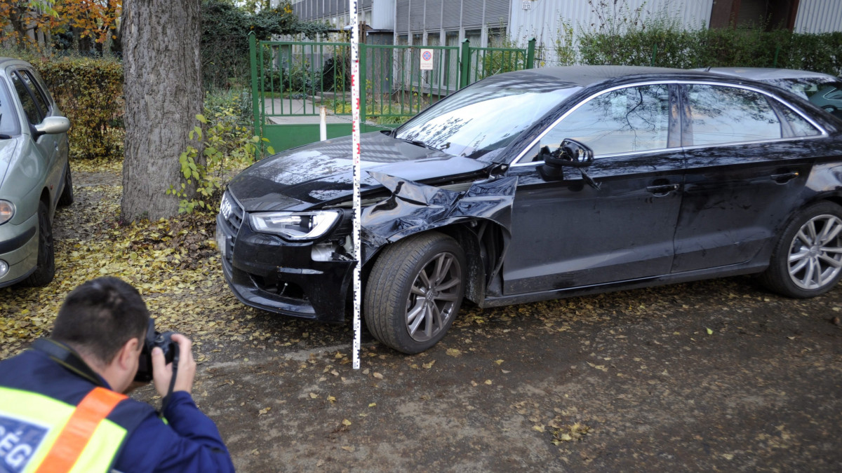 Rendőr helyszínel egy összetört személyautó mellett a XIV. kerületi Nagy Lajos király útján 2016. november 7-én, miután az autó eddig tisztázatlan körülmények halálra gázolt egy idős férfit a Füredi utcában.
