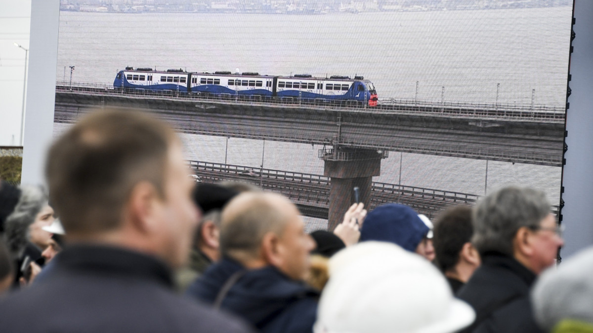 A Tamany-félszigeten ünneplő emberek hatalmas kivetítőn nézik, amint az első vonat áthalad a Krími hídon Vlagyimir Putyin orosz elnökkel a fedélzetén az építmény vasútpályájának avatóünnepségén 2019. december 23-án. A Kercsi-szoros két partját összekötő, 19 kilométer hosszú létesítményen napi 40 ezer gépkocsi és 47 vonat haladhat majd át. A híd éves utasforgalma becslések szerint 13 millió fő, teherforgalma 13 millió tonna lesz.