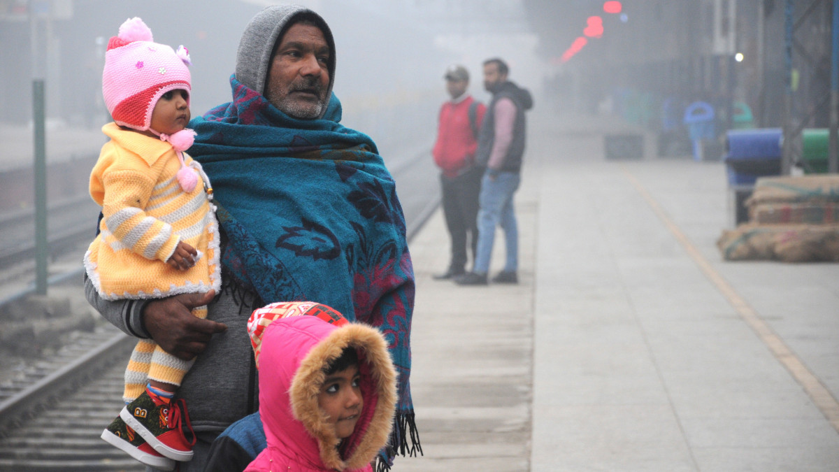 Melegen öltözött utasok egy amritszári vasútállomáson egy hideg és ködös reggelen, 2019. december 17-én, az Észak-Indiában uralkodó hideghullám idején.