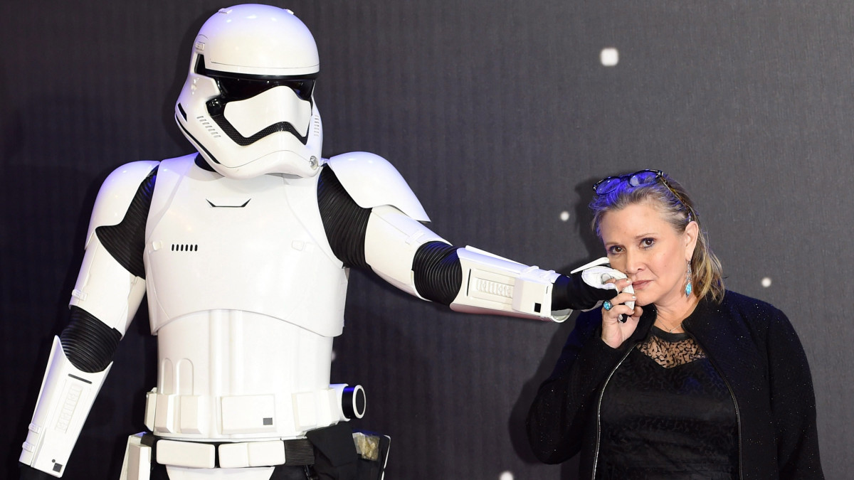 London, 2016. december 24. A 2015. december 16-ai képen Carrie Fisher amerikai színésznő a Csillagok Háborúja filmekből ismert rohamosztagos karakter kezét érinti az arcához az űreposz Az ébredő erő (Star Wars - The Force Awakens) című részének európai premierjén, a londoni Leicester téren. A filmsorozatban Leia hercegnő szerepét játszó 60 éves színésznő 2016. december 23-án szívrohamot kapott egy Londonból Los Angelesbe tartó járaton, a repülőgépen újraélesztették, és kórházba vitték. (MTI/EPA/Facundo Arrizabalaga)  *** Local Caption *** 53067674