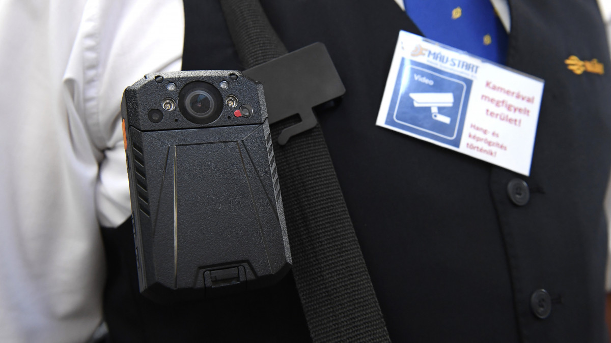 Testkamera és a felvételre figyelmeztető kártya a bemutató sajtótájékoztatón, a Keleti pályaudvaron 2019. augusztus 30-án. A vasúti menetjegyellenőröket ért támadások miatt szeptember 1-jétől 103 új testkamerát kapnak országszerte a MÁV-START Zrt. jegykezelői.