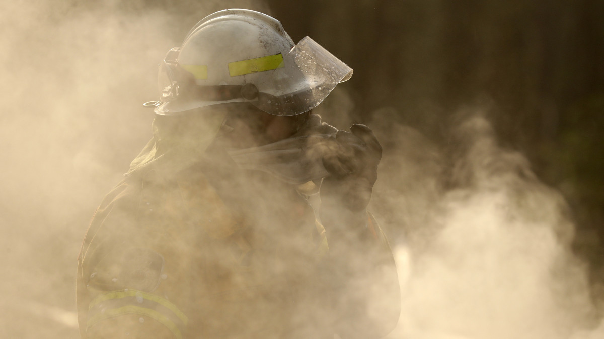 Tűzoltó védi arcát az égő növényzet füstjétől az Új-Dél-Wales állambeli Bendalongban 2020. január 3-án. Az október óta tomboló bozót- és erdőtüzek miatt emberek tízezreit kell kimenteni Ausztrália délkeleti térségéből. Ausztrália-szerte 5,5 millió hektárnyi földterület égett le, 18 ember meghalt és több mint ezer ház vált a lángok martalékává.