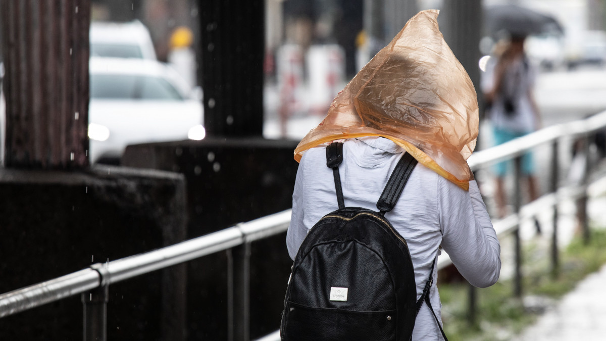 Műanyag zacskóval a fején megy egy nő a szakadó esőben Berlinben 2019. augusztus 2-án.