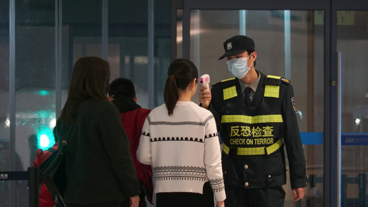 Infravörös hőmérővel méri az távozó utasok testhőmérsékletét egy dolgozó a vuhani nemzetközi repülőtéren 2020. január 21-én. A Pekingben és a dél-kínai Sencsenben is felbukkant új, tüdőgyulladást okozó vírus kiindulópontjának számító közép-kínai Vuhanban jelentősen megugrott a fertőzöttek száma, a vírusfertőzés eddig legkevesebb négy ember halálát okozta.
