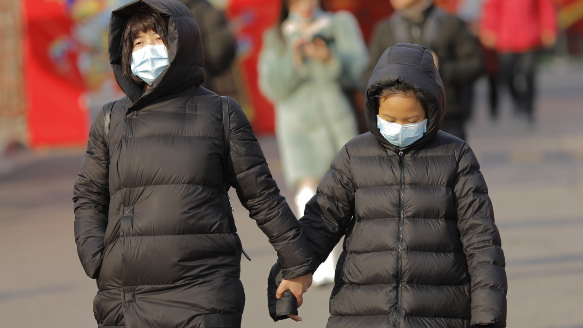 Védőmaszkos gyalogosok Pekingben 2020. január 21-én. A kínai fővárosban és a dél-kínai Sencsenben is felbukkant új, tüdőgyulladást okozó vírus kiindulópontjának számító közép-kínai Vuhanban jelentősen megugrott a fertőzöttek száma, a vírusfertőzés eddig legkevesebb négy ember halálát okozta.