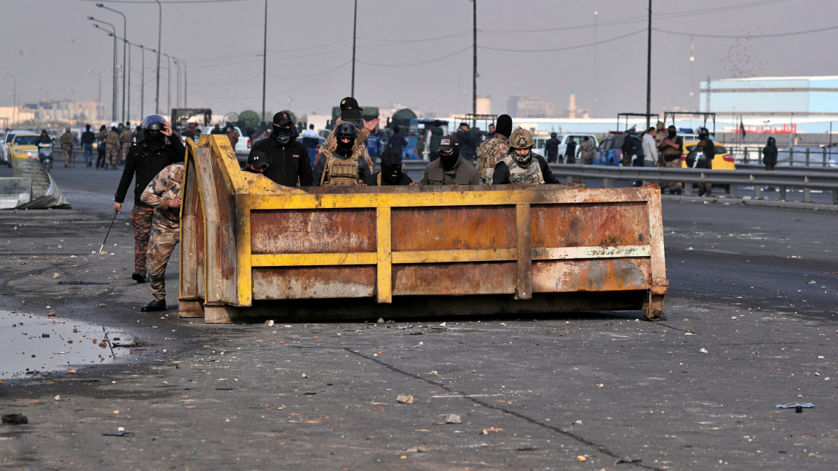 Iraki rendőrök fedezékben a kormányellenes tüntetőkkel való összecsapások során Bagdadban 2020. január 21-én. Az új kormányfő kinevezését követelő tüntetők és a rendőrök összecsapásaiban ezen a napon legkevesebb nyolc tüntető életét veszítette és ötvennél is többen megsebesültek Irakban.