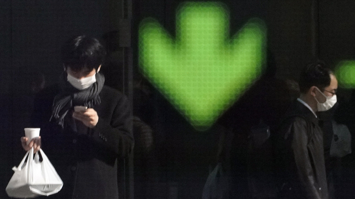Maszkot viselő járókelők a tokiói tőzsde kijelzője előtt 2020. február 3-án. Tokióban a 225 válogatott részvény Nikkei mutatója 1,09 százalékos veszteségben zárt. Az új koronavírus globális kereskedelemre gyakorolt hatása miatt esnek az ázsiai indexek.