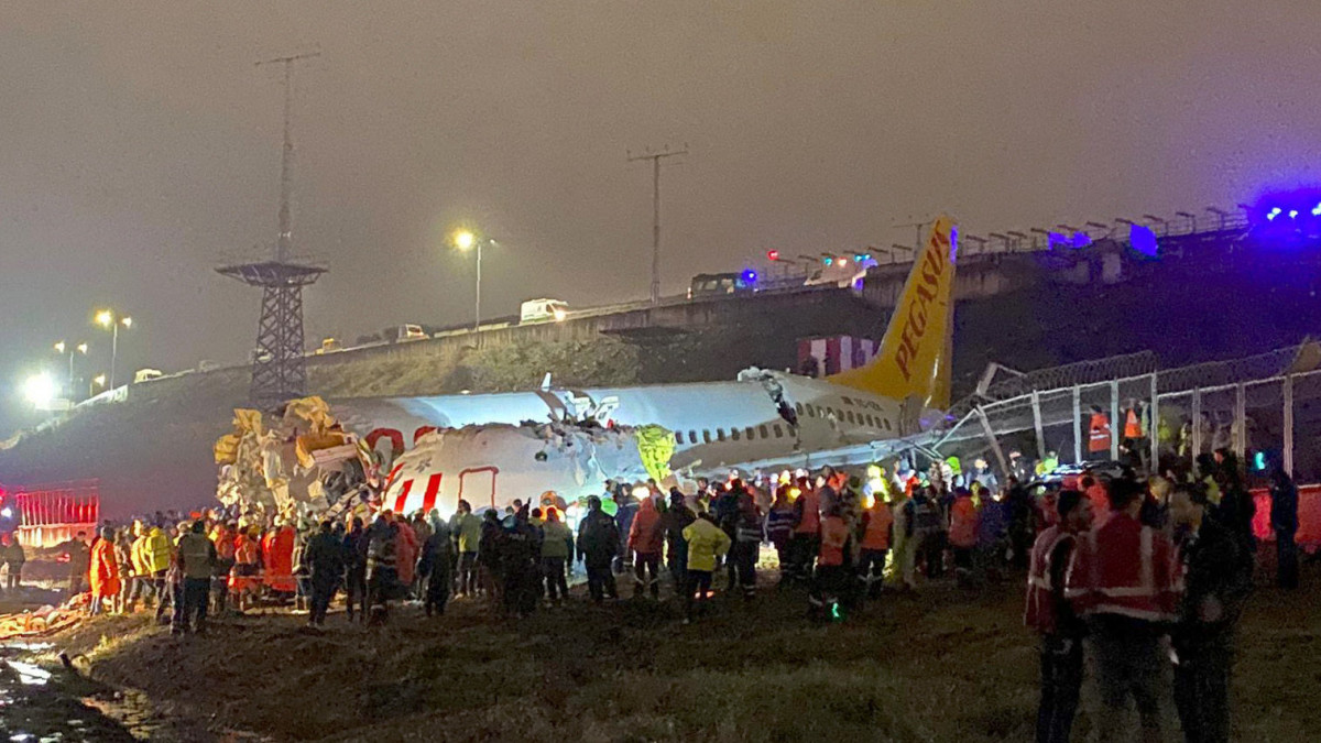 A roncs mellett dolgoznak mentők és tűzoltók az isztambuli Sabiha Gökcen repülőtéren 2020. február 5-én, miután a Pegasus török légitársaság egyik utasszállító gépe túlfutott a leszállópályán, falnak ütközött és kettétört. Halálos áldozatai nincsenek a balesetnek, leglább 21 ember megsérült.