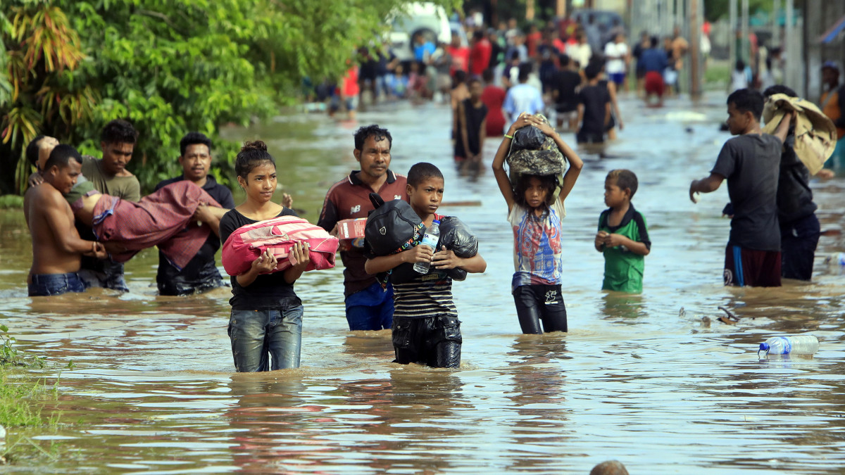 Kelet-timori lakosok gyalogolnak egy vízzel elárasztott utcán a kelet-timori főváros közelében lévő Tasitoluban 2020. január 23-án. A heves esőzések nyomán a fővárost és környező településeket árvíz öntötte el.