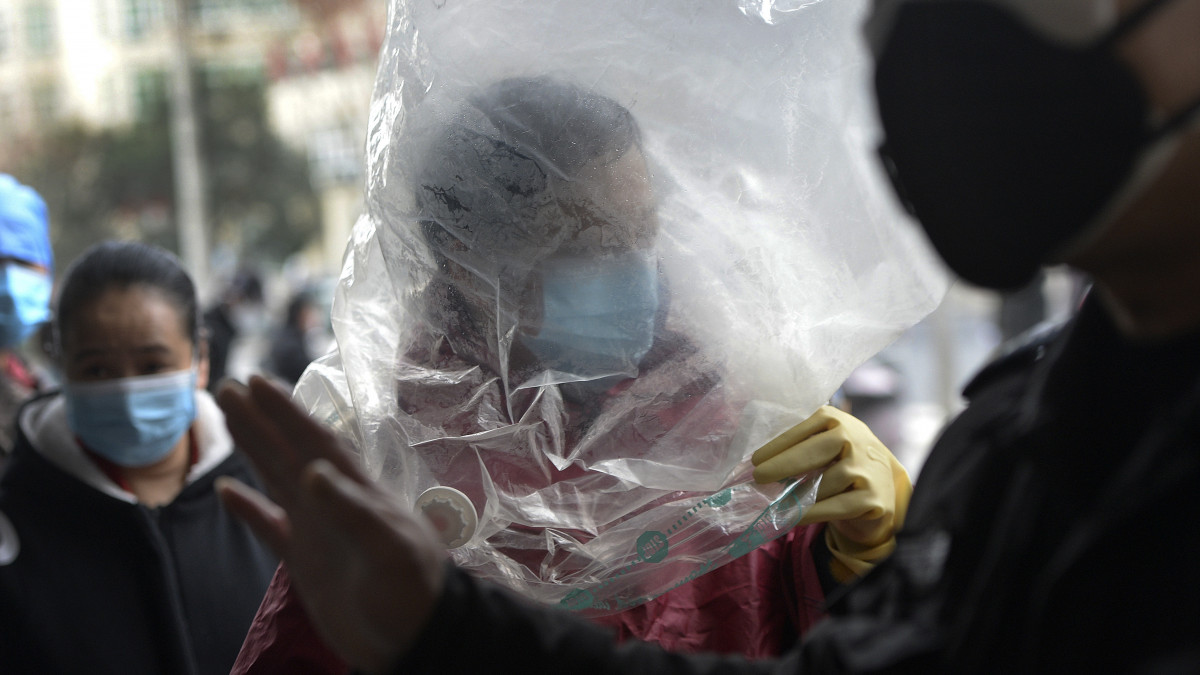A szájmaszk mellett a fejére húzott nejlonzacskóval is védekezik egy férfi, mielőtt bemegy egy vuhani ABC-áruházba 2020. február 10-én. A koronavírus előidézte tüdőgyulladás halálos áldozatainak száma 908-ra emelkedett Kínában, a legtöbben a járvány gócpontjában, Hupej tartományban és annak székhelyén, Vuhanban hunytak el.
