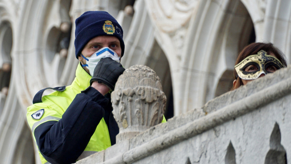 A koronavírus elleni védekezésül szájmaszkot visel egy rendőr a velencei karneválon a Szent Márk tér közelében 2020. február 23-án. Luca Zaia, az északkelet-olaszországi Veneto tartomány kormányzója ezen a napon bejelentette, hogy a koronavírus-járvány olaszországi terjedése miatt megszakítják a velencei karnevált. A tüdőgyulladást okozó, Covid-19-nek elnevezett újfajta koronavírus fertőzöttjeinek száma 115 fölé emelkedett Olaszországban.