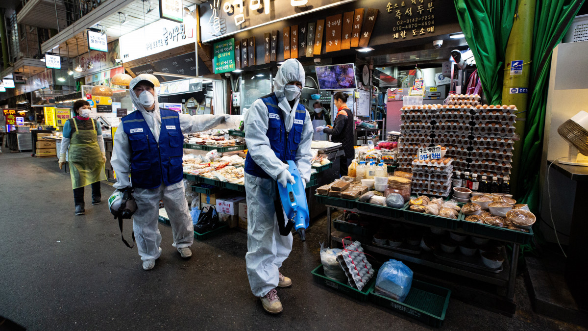 A járványügyi hatóság munkatársai fertőtlenítőszert permeteznek a szöuli Mangvon piacon 2020. február 24-én. Dél-Koreában 763-ra emelkedett a tüdőgyulladást okozó új koronavírussal fertőzöttek száma, és eddig összesen hét ember halt bele a betegségbe.