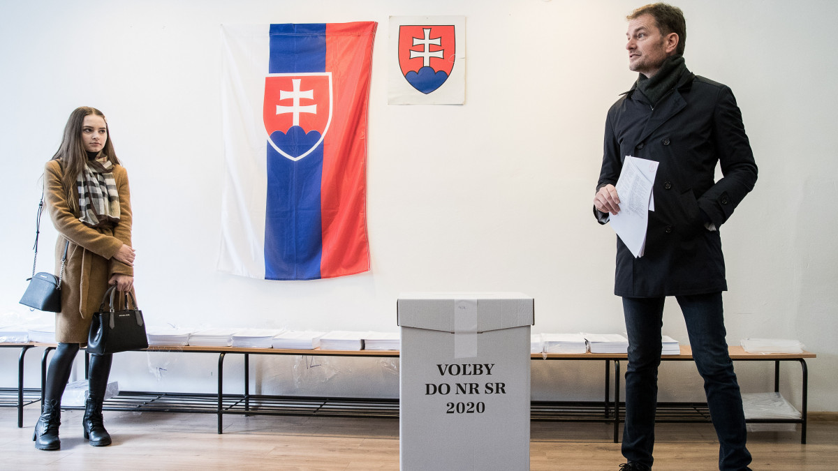 Igor Matovic, az Egyszerű Emberek és Független Személyiségek nevű párt elnöke (j), mielőtt voksol egy nagyszombati szavazóhelyiségben 2020. február 29-én, a szlovák parlamenti választások napján. Balról Matovic lánya, Rebeka.