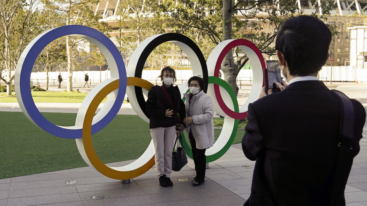 Védőmaszkot viselő látogatók az olimpiai ötkarikánál a 2020-as tokiói olimpia központi létesítménye, az új Nemzeti Stadion előtt 2020. február 27-én. Szuga Josihide, a japán kormány szóvivője előző nap megerősítette, hogy a Nemzetközi Olimpiai Bizottság folytatja az olimpia előkészítését az előzetes menetrend alapján. Japánban eddig hat ember vesztette életét a járványban, a fertőzöttek száma meghaladja a 890-et.