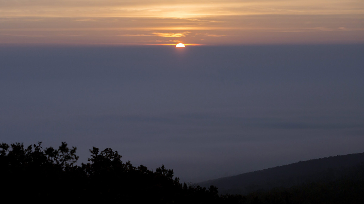 Napfelkelte a ködbe burkolózott Pilis felett Pilisborosjenő közelében a Nagy-Kevélyen készült felvételen 2015. október 25-én reggel.