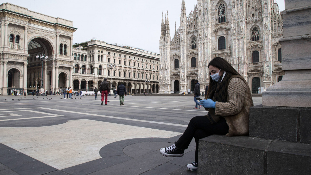 Védőmaszkos nő nézi a telefonját a milánói dóm előtt 2020. március 10-én. A tüdőgyulladást okozó koronavírus terjedésének megfékezésére az olasz kormány az ország egész területére kiterjesztette a legmagasabb fokozatú óvintézkedéseket. A járvány következtében eddig 483 ember halt meg Olaszországban.
