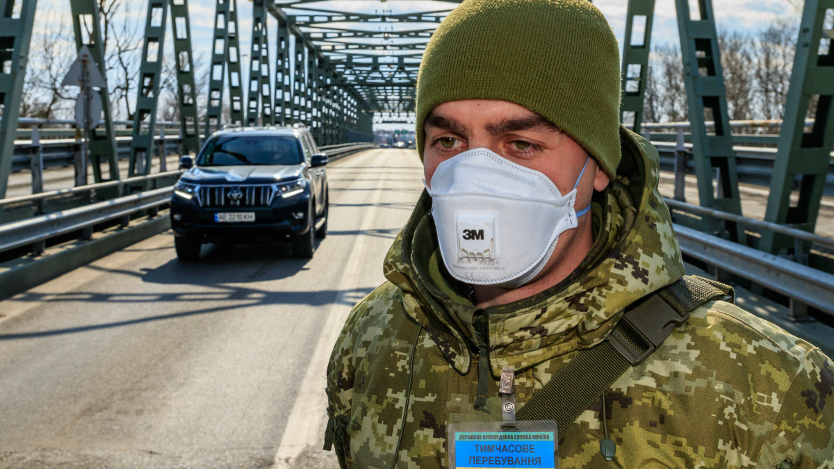 Védőmaszkot viselő ukrán határőr a Csaphoz közeli Tisza közúti határátkelőn az ukrán-magyar határon 2020. február 25-én. Védőmaszkot viselő ukrán határőrök mérik egy belépő gépkocsivezető testhőmérsékletét a Csaphoz közeli Tisza közúti határátkelőn, az ukrán-magyar határon 2020. február 25-én. Ukrajna is készenléti állapot vezetett be a tüdőgyulladást okozó új koronavírus-járvány elkerülésére az olaszországi fertőzések miatt. A határokon fokozott ellenőrzésnek vetik alá azokat, akik Olaszországból érkeznek.