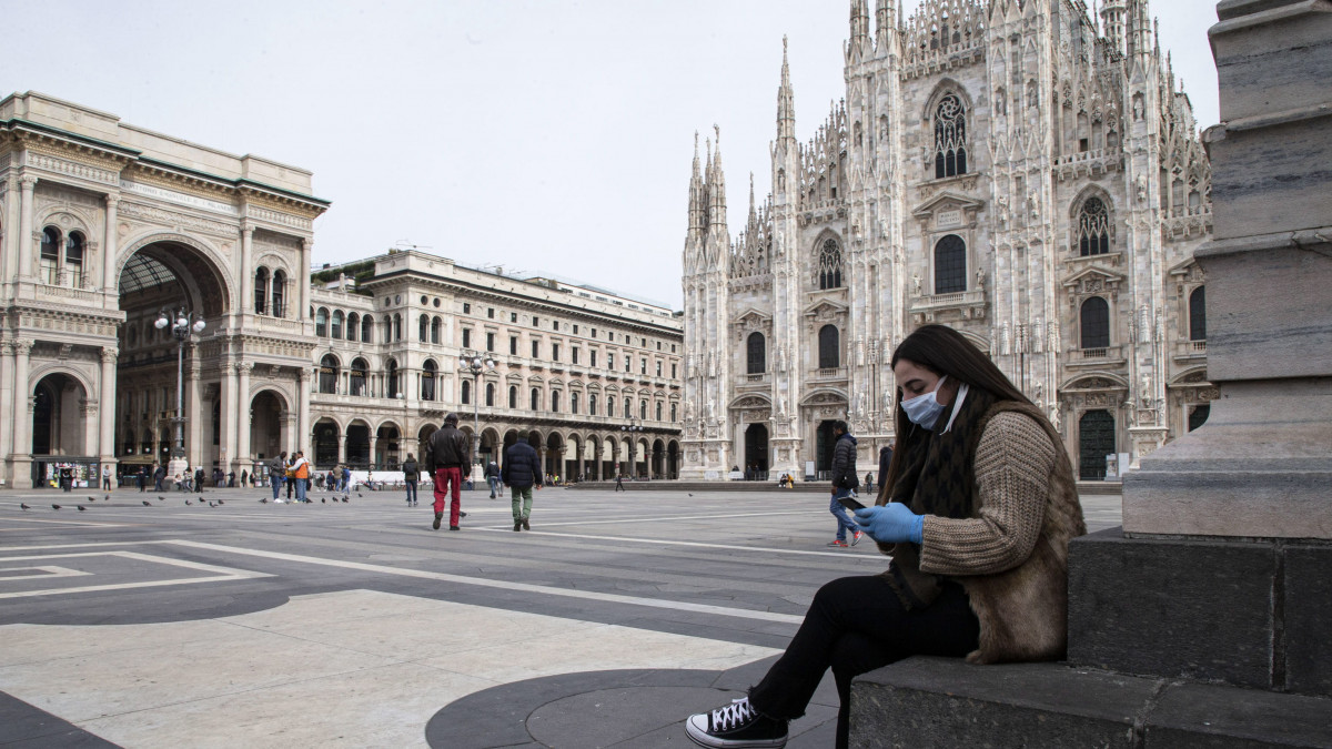 Védőmaszkos nő nézi a telefonját a milánói dóm előtt 2020. március 10-én. A tüdőgyulladást okozó koronavírus terjedésének megfékezésére az olasz kormány az ország egész területére kiterjesztette a legmagasabb fokozatú óvintézkedéseket. A járvány következtében eddig 483 ember halt meg Olaszországban.
