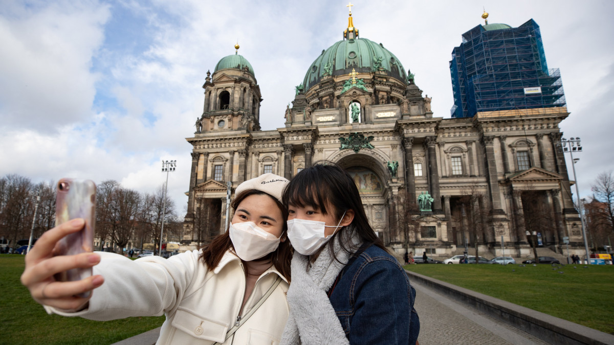 Hongkongi turisták védőmaszkban fényképezkednek a berlini dóm előtt 2020. március 13-án. A tüdőgyulladást okozó új koronavírus járványának megfékezésére a német fővárosban április 19-ig bezáratnak minden múzeumot.