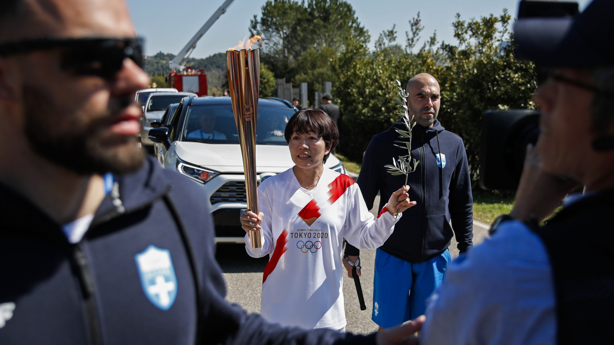 A staféta második tagja, Nogucsi Midzuki olimpiai bajnok japán maratoni futó viszi fáklyát az olimpiai láng fellobbantási ünnepsége után Héra templománál, az eredeti olimpiai játékok helyszínén, az ókori Olümpiában 2020. március 12-én. A tüdőgyulladást okozó új koronavírus járványa miatt az ünnepséget a nyilvánosság kizárásával, mindössze száz meghívott vendég jelenlétében tartották meg.