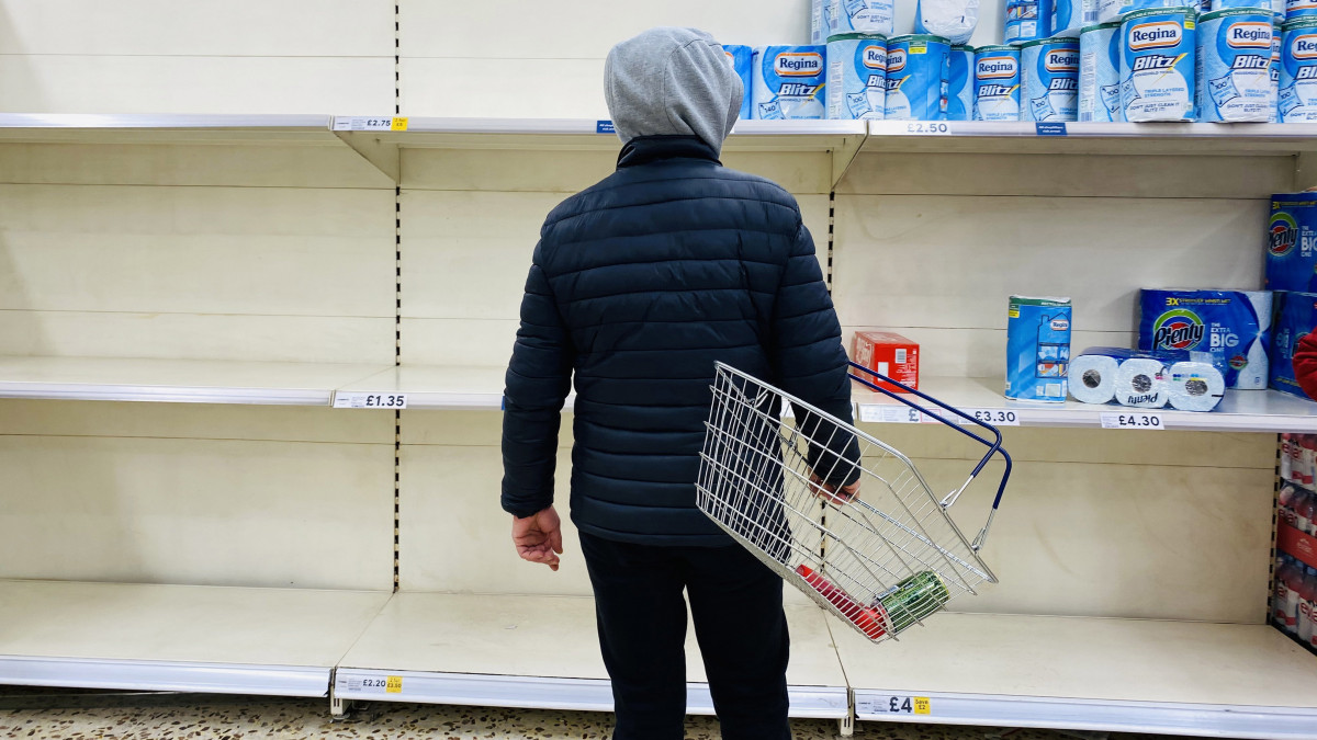 Üres polcok előtt áll egy vásárló egy londoni szupermarketben 2020. március 15-én. A koronavírus-járvány terjedése miatt Nagy-Britanniában az emberek elkezdték felvásárolni az élelmiszereket.