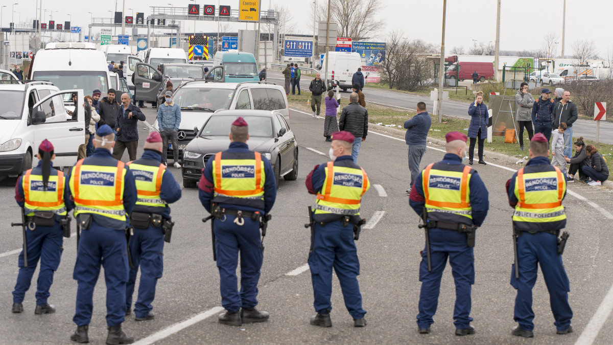 Rendőrök a hegyeshalmi közúti határátkelőnél 2020. március 17-én. Délben csaknem húsz kilométeres torlódás alakult ki Hegyeshalomnál a közúti határátkelő osztrák oldalán. A román külügyminiszter humanitárius folyosó megnyitását kérte, hogy Magyarországon keresztül utazhasson haza az a több mint 3500 román állampolgár, akik a határátkelőnél akadtak el. A koronavírus-járvány miatt ettől a naptól csak magyar állampolgárok léphetnek be Magyarország területére a személyszállítás keretében, de a teherszállítás tekintetében a belépéseket nem korlátozzák.