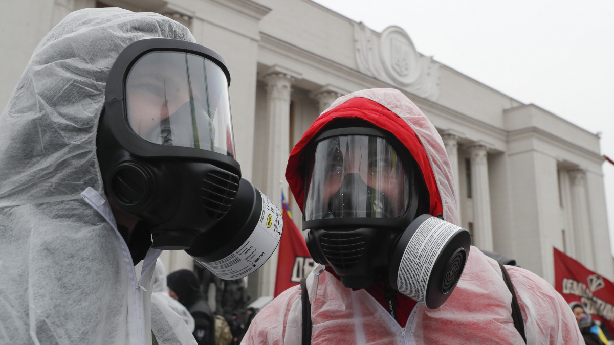 A koronavírus-járvány miatt védőruhát és légzőmaszkot viselő ukrán aktivisták tüntetnek a parlament épülete előtt Kijevben 2020. március 17-én. A demonstrálók azt követelik, hogy a parlamenti képviselők helyezzék magukat karantén alá és függesszék fel a törvényhozást. Az ukrán parlament elfogadta a koronavírus elleni intézkedésekről szóló törvényjavaslatot, melyben elrendelték a legtöbb üzlet bezárását, korlátozzák a tömegközlekedést és bevezetik az otthoni munkavégzést, ahol lehetséges.