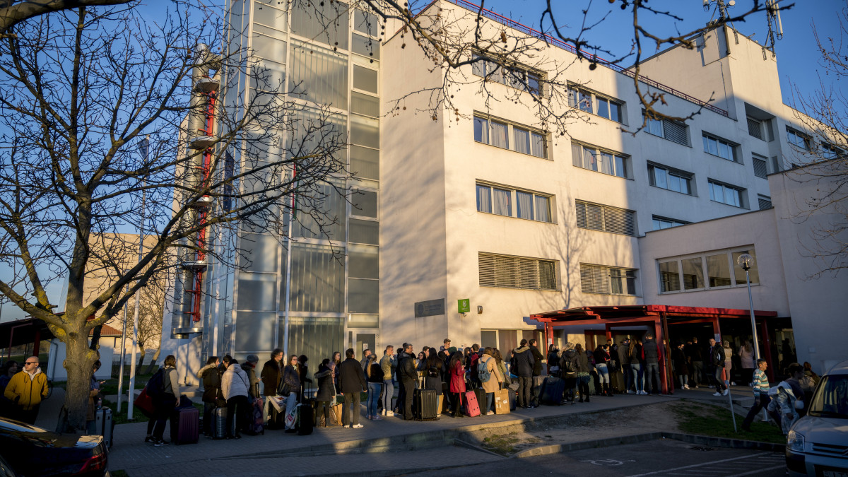 Hallgatók várakoznak a kiköltözésre a Pécsi Tudományegyetem Szalay László Kollégium épülete előtt Pécsen 2020. március 16-án. A koronavírus-járvány miatt a kormány intézménylátogatási tilalmat rendeltek el a magyarországi egyetemeken, csak távoktatásban folytatható az oktatás.