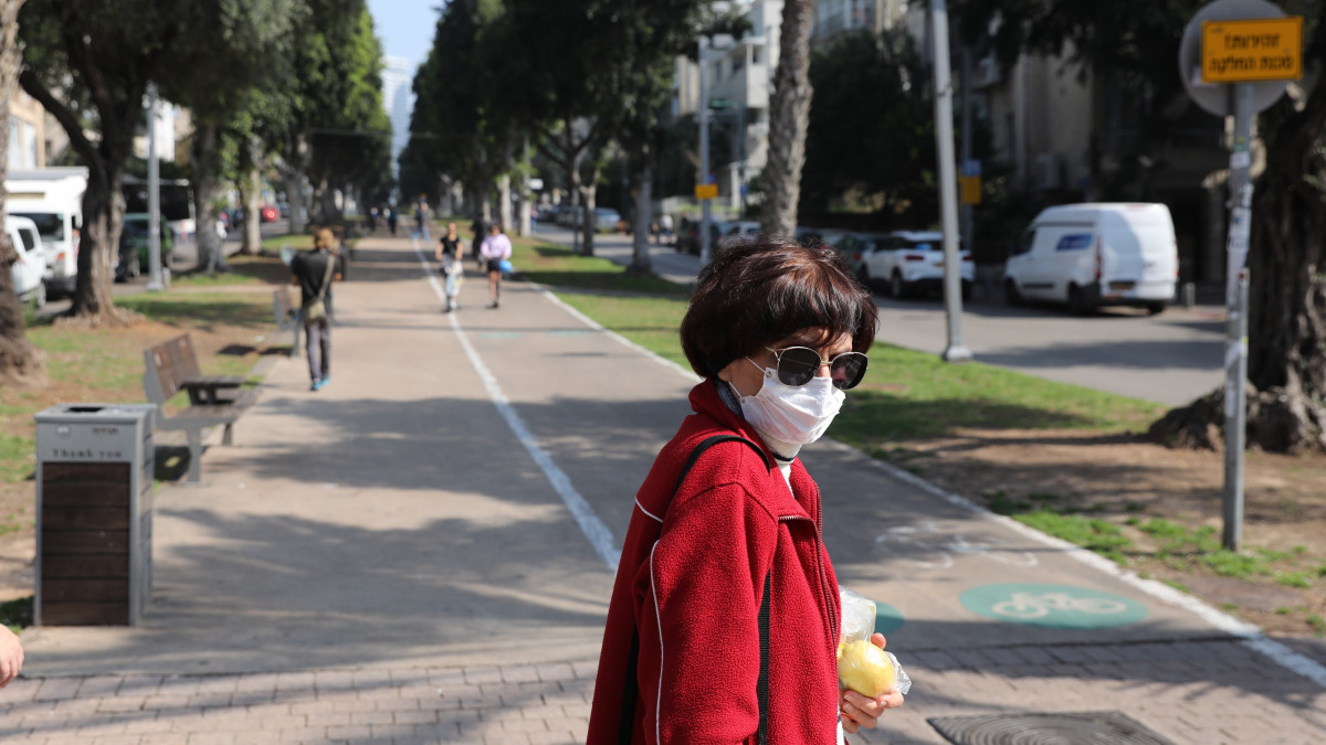 Az új koronavírus járványa miatt védőmaszkot visel egy járókelő Tel-Avivban 2020. március 16-án.
