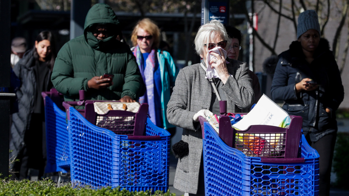 A koronavírus-járvány miatt védőmaszkot viselő emberek állnak sorban egy szupermarket előtt a belgiumi Drogenbosban 2020. március 18-án. A belga kormány előző este kijárásra vonatkozó korlátozásokat rendelt el a járvány terjedésének lelassítása érdekében.