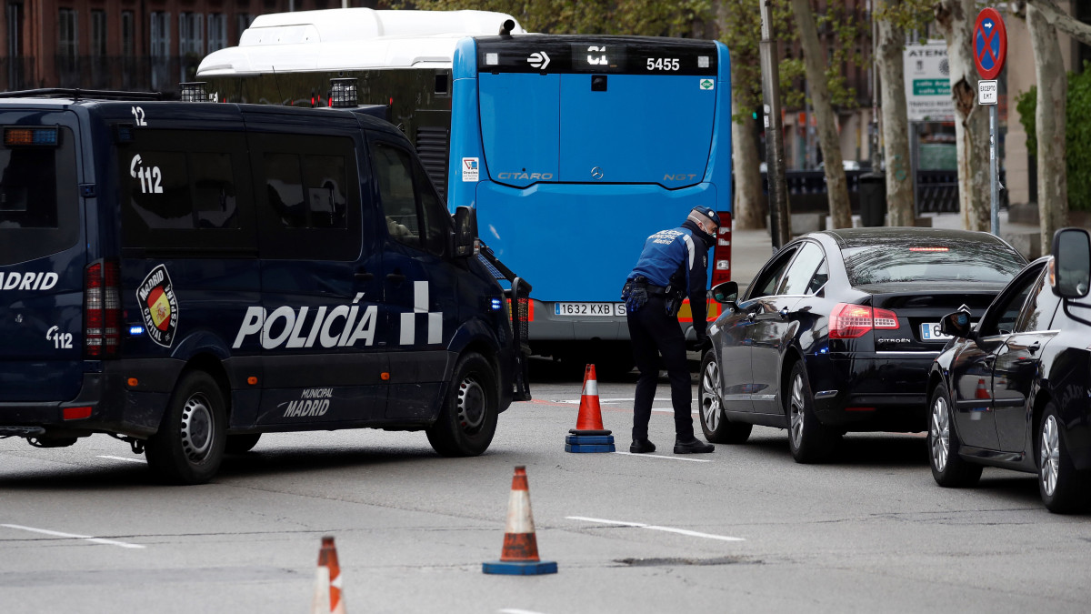 Rendőrök ellenőriznek egy autóvezetőt Madrid belvárosában 2020. március 20-án. Spanyolországban a rendőrség és a csendőrség a hat napja elrendelt lakhelyelhagyási korlátozások betartásának ellenőrzését nagy erőkkel végzi. Az országban eddig 20412 fertőzöttet regisztáltak és 1041 ember vesztette életét.