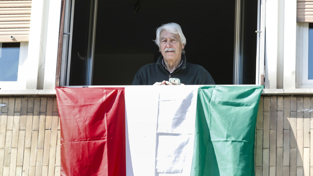 Nemzeti színű zászlót lógat ki idős férfi lakása ablakából Rómában a koronavírus-járvány miatt bevezetett kijárási tilalom idején, 2020. március 20-án. Olaszországban eddig 41035 fertőzött személyt regisztráltak, a halálos áldozatok száma 3405-re emelkedett.