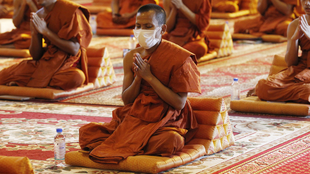 A koronavírus-járvány miatt védőmaszkot viselő buddhista szerzetesek imádkoznak egy phnompeni imaházban 2020. március 23-án. A kambodzsai egészségügyi hatóságok eddig 86 koronavírussal fertőzött személyt regisztráltak.