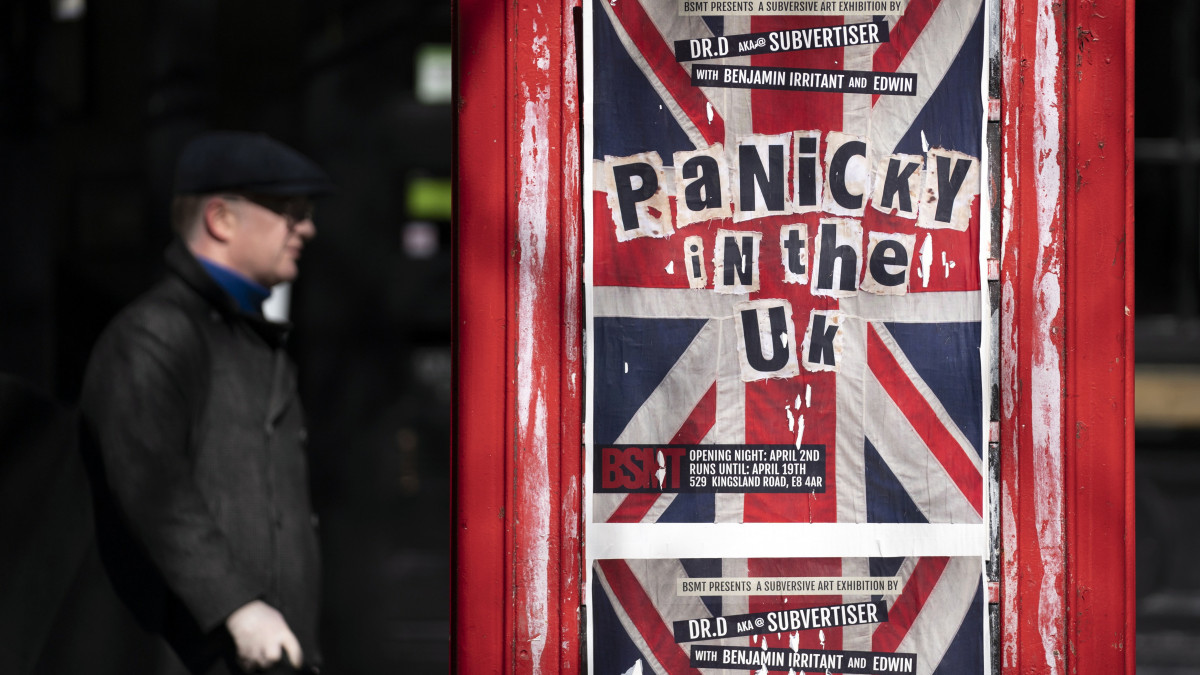 Gyalogos sétál egy telefonfülkére ragasztott Pánik az Egyesült Királyságban feliratú plakát előtt Londonban 2020. március 23-án. A felirat megjelenítése a Sex Pistols korábbi brit punk rock zenekar Anarchy in the U.K. című kislemezére emlékeztet. A londoni alsóház elé került az új koronavírus okozta járvány megfékezését célzó törvényjavaslat, amely lehetővé teszi a fertőzésgyanús emberek kényszerkivizsgálásának elrendelését, a repülőterek időleges bezárását és sok egyéb rendkívüli intézkedést. Nagy-Britanniában eddig 5683 koronavírussal fertőzött személyt regisztráltak és 289 ember halt bele a betegségbe.