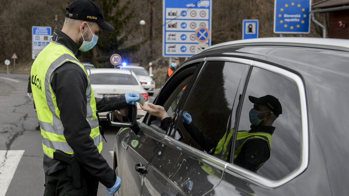 Szlovák rendőr egy autós iratait ellenőrzi a Somoskőújfalui és Sátorosbánya közötti határátkelőhelyen 2020. március 13-án. A koronavírus terjedésének megakadályozása érdekében a szlovák kormány reggel 7 órától a közúti határátkelőin - a lengyel határszakaszt kivéve - visszaállítja a határellenőrzést. Csak azokat engedik be Szlovákiába, akik szlovák állampolgárok, és akiknek az országban tartózkodási engedélyük van. Minden külföldről érkezőnek 14 napos karanténba kell vonulnia.
