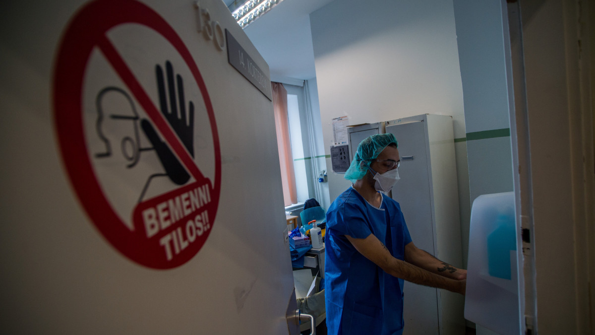 Védőmaszkot viselő ápoló fertőtleníti kezét, miután az izolációs teremben dolgozott a koronavírussal fertőzött betegek fogadására kialakított egyik osztályon az Országos Korányi Pulmonológiai Intézetben 2020. március 24-én.