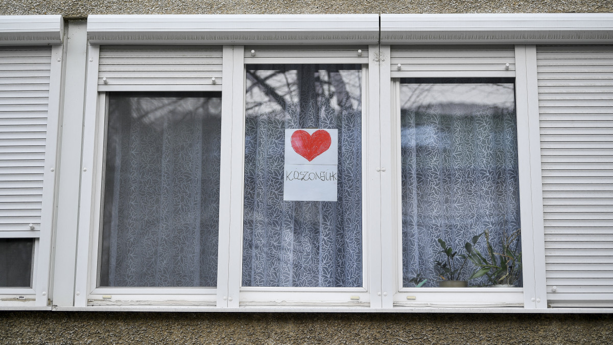 Kiragasztott köszönjük felirat és piros szív egy debreceni társasház lakásának egyik ablakában 2020. március 25-én. A lakók a koronavírus-járvány elleni küzdelemben helytálló egészségügyi dolgozóknak mondanak így köszönetet.