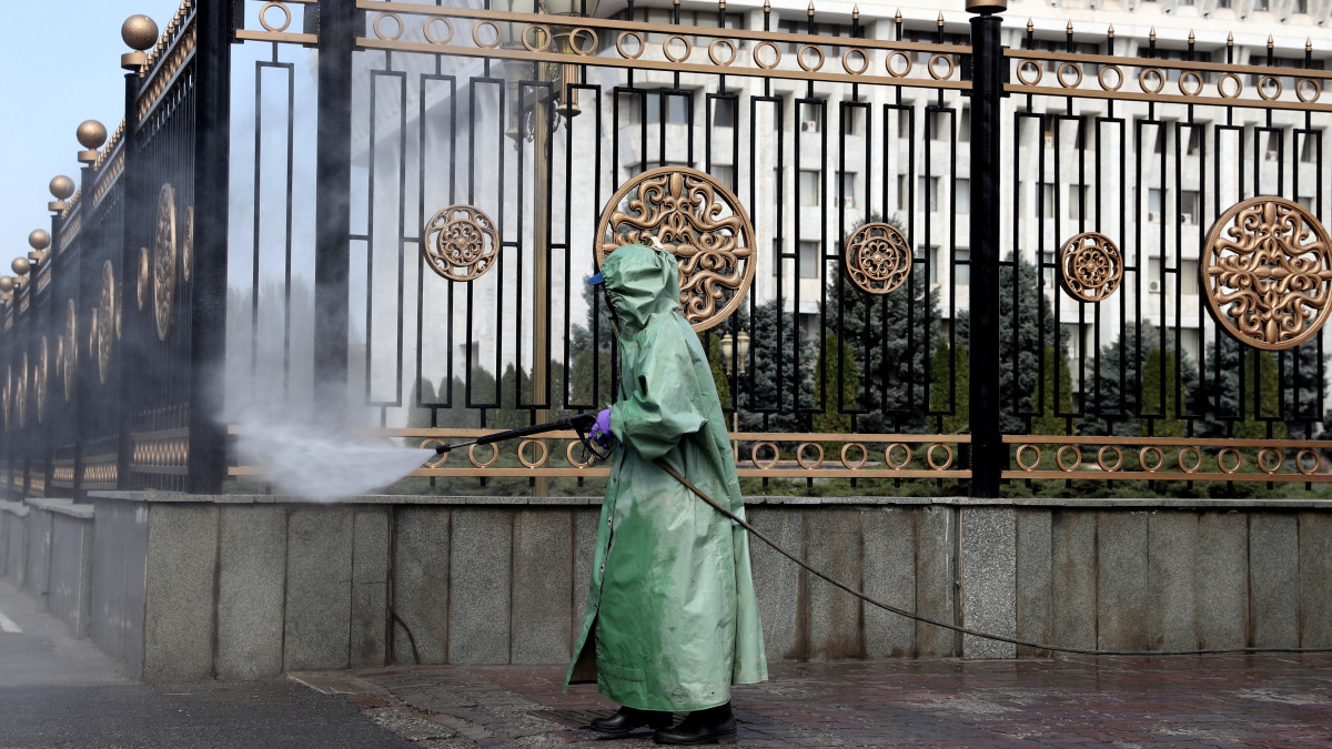 Köztisztasági dolgozó fertőtleníti a kerítést a kirgiz parlament előtt Biskekben 2020. március 26-án. Kirgizisztán veszélyhelyzetet hirdetett, miután az országban 44 embernél kimutatták a koronavírus-fertőzést.