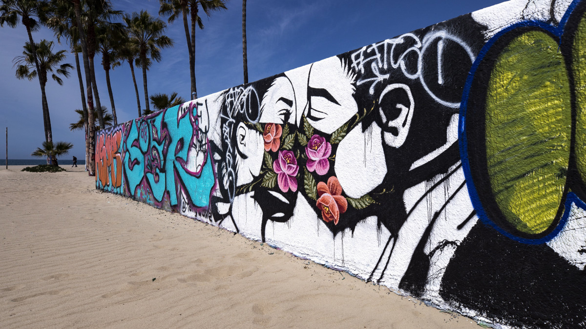 Venice, 2020. március 29.Védőmaszkban csókolózó párt ábrázoló falfestmény a kaliforniai Venice tengerpartján 2020. március 28-án. Eric Garcetti Los Angeles-i polgármester elrendelte a strandok lezárását a koronavírus-járvány elleni küzdelem hatékonyság érdekében.