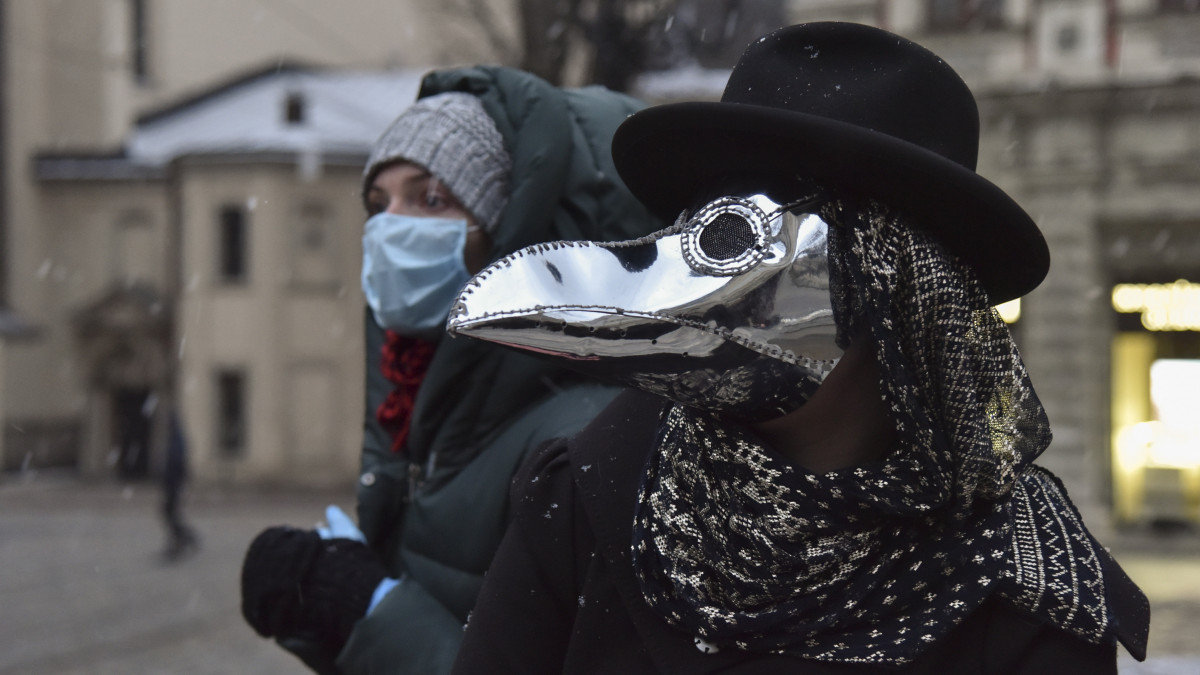 Pestisdoktor maszkot visel egy nő a nyugat-ukrajnai Lviv városban 2020. március 22-én, az új típusú koronavírus-járvány idején. A középkorban a pestisjárvány sújtotta települések betegeit kezelő pestisdoktorok a madárcsőrre emlékeztető maszkba illatos növényeket raktak, hogy megakadályozzák a rossz levegő belélegzését.