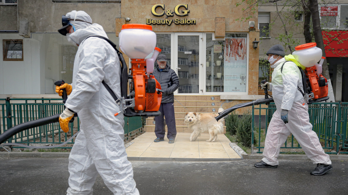 A koronavírus-járvány megfékezésének érdekében egy bukaresti utcát fertőtlenítenek védőruhás városi alkalmazottak 2020. március 31-én.
