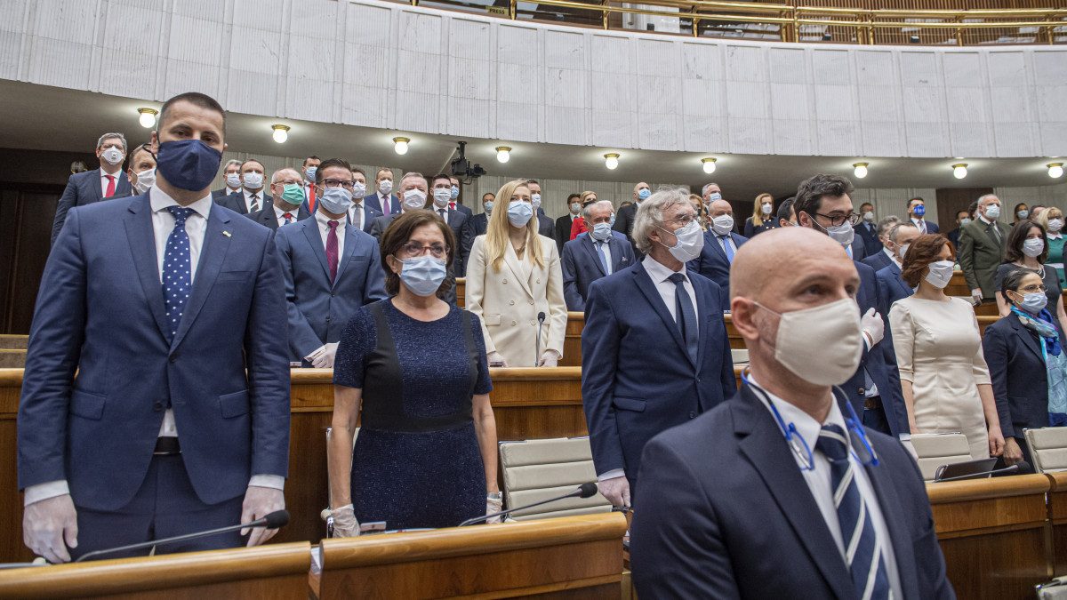 Az új koronavírus járványa miatt védőmaszkot és gumikesztyűt viselő képviselők a parlament alakuló ülésén a pozsonyi ülésteremben 2020. március 20-án.
