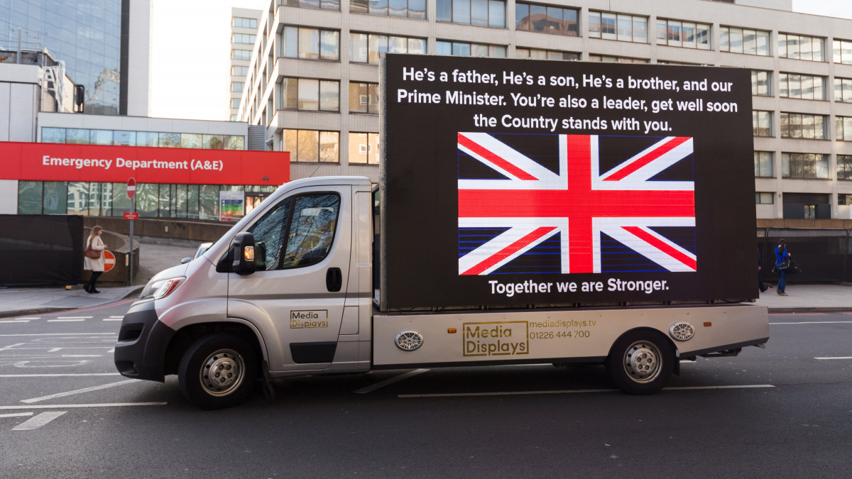 Boris Johnson brit miniszterelnököt támogató üzenet egy kisteherautó oldalán a londoni St. Thomas Kórház előtt 2020. április 7-én. Az új koronavírussal fertőzött kormányfőt az előző este átszállították a londoni St. Thomas Kórház intenzív osztályára, és akadályoztatása alatt Dominic Raab külügyminiszter látja el a kormányfői feladatokat.